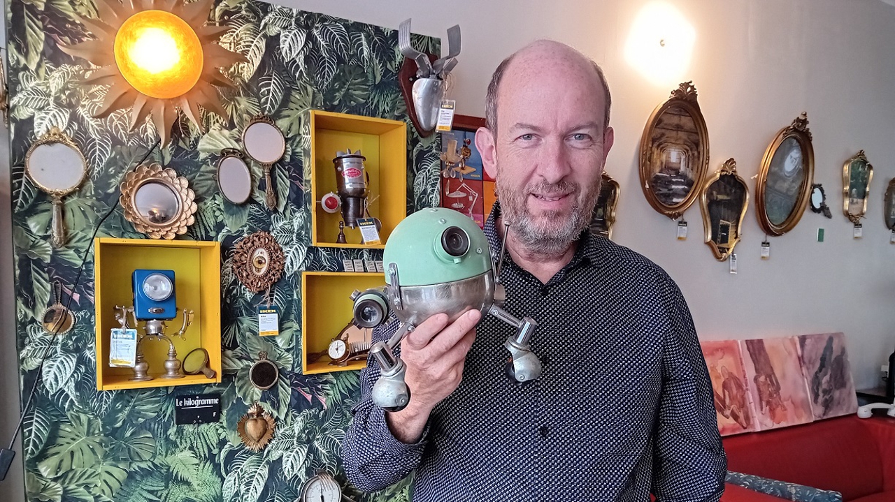 Dominique Hermier dans sa galerie-boutique de Blois, tenant un robot à objectif